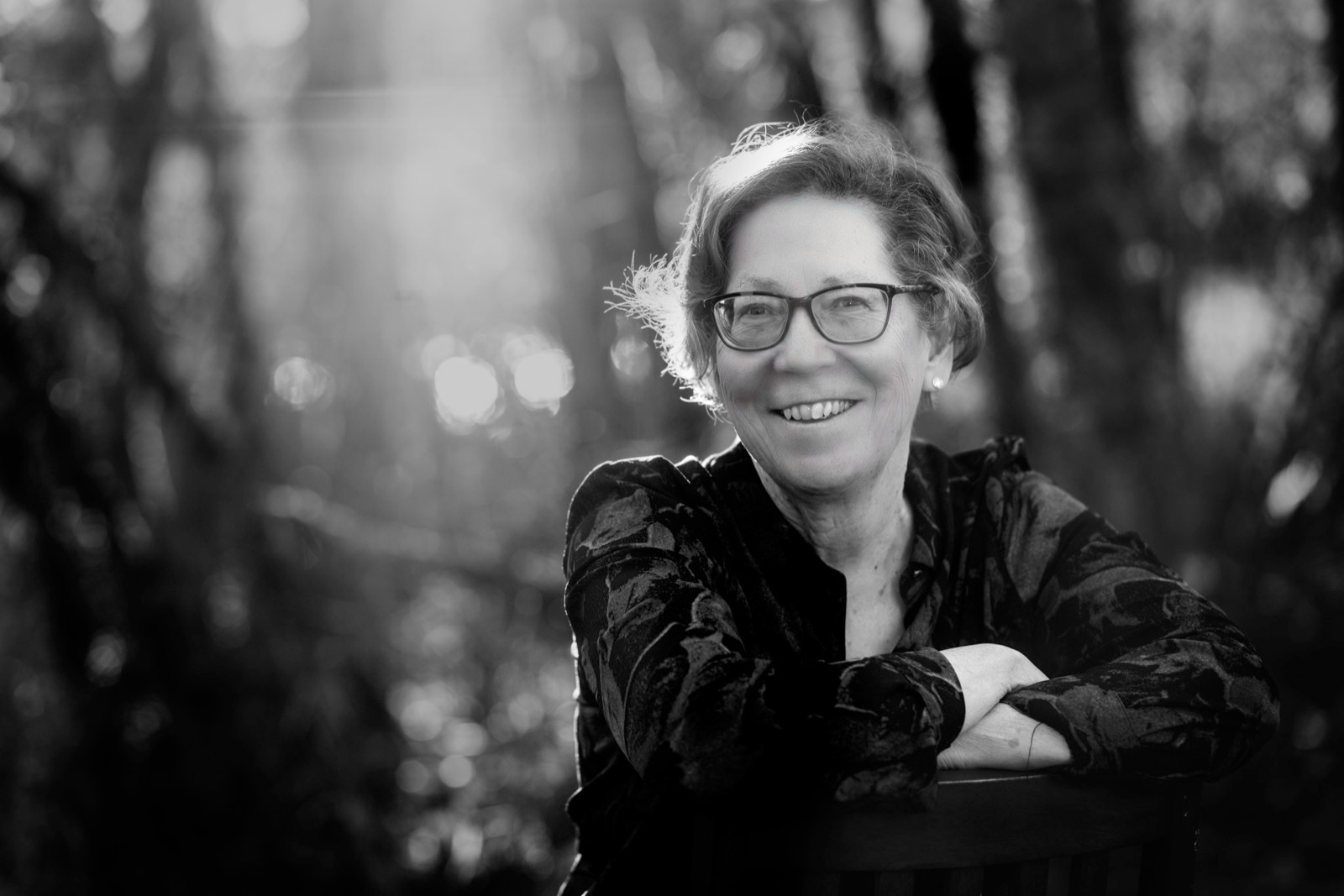 Black-and-white portrait of Susan Palmer smiling in woodland light